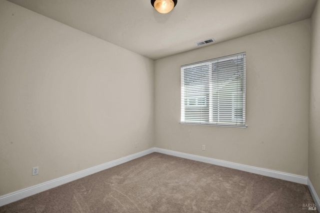 carpeted spare room featuring baseboards and visible vents