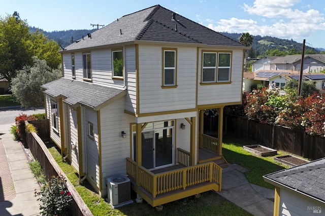 back of property featuring cooling unit, a vegetable garden, a shingled roof, and a fenced backyard