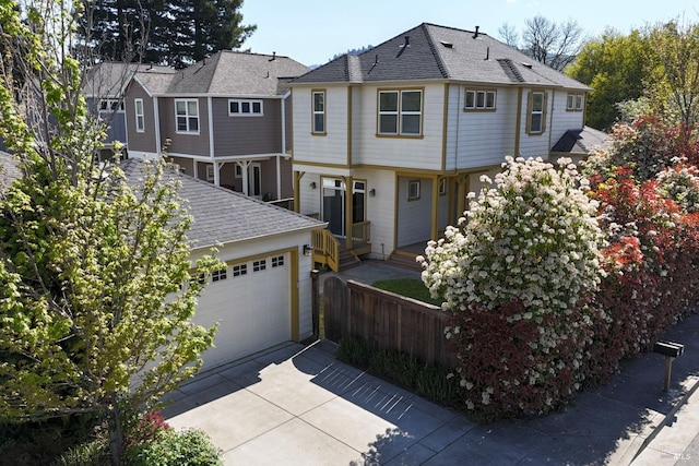 view of front facade with fence, concrete driveway, and an attached garage
