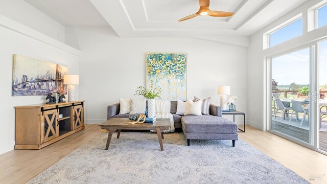 living area featuring wood finished floors, a ceiling fan, a tray ceiling, and baseboards
