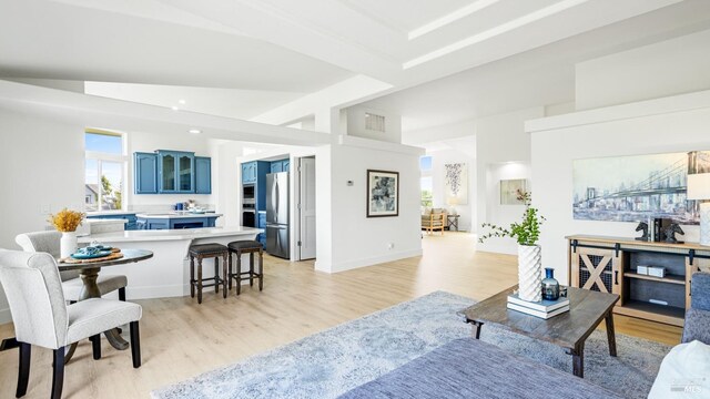 living area with visible vents, light wood-style floors, and lofted ceiling