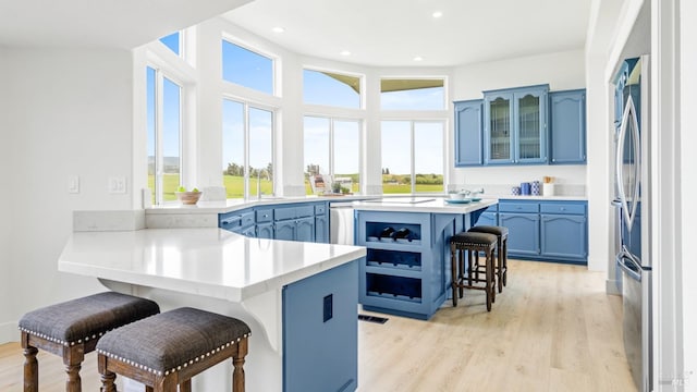 kitchen with a breakfast bar, a peninsula, blue cabinets, and light countertops