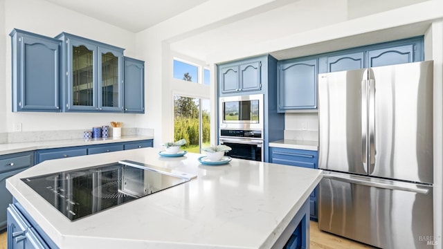 kitchen with appliances with stainless steel finishes, blue cabinets, and a center island