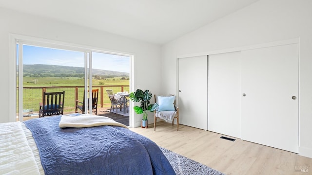 bedroom with wood finished floors, access to outside, a closet, visible vents, and lofted ceiling