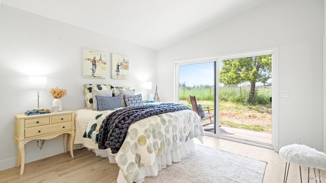 bedroom featuring access to outside, lofted ceiling, and light wood-style flooring