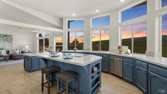 kitchen with blue cabinets, stainless steel dishwasher, a breakfast bar area, a kitchen island, and a sink