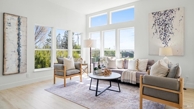 living area with wood finished floors, a healthy amount of sunlight, and a high ceiling