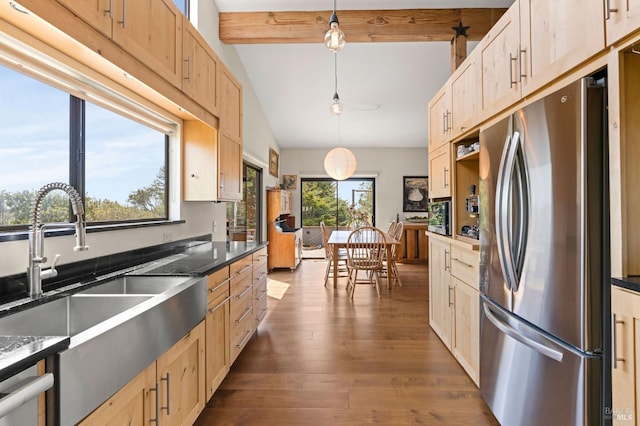kitchen with a sink, dark countertops, light brown cabinets, freestanding refrigerator, and dark wood-style flooring