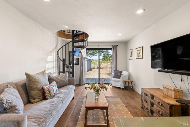 living area featuring baseboards, recessed lighting, wood finished floors, and stairs