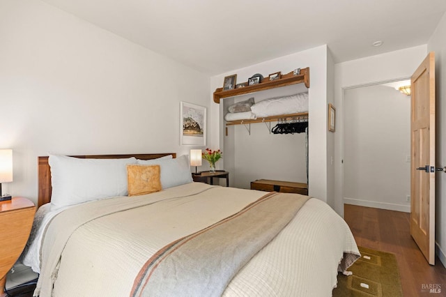 bedroom featuring baseboards, wood finished floors, and a closet