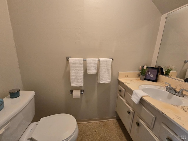 half bath with baseboards, toilet, and vanity
