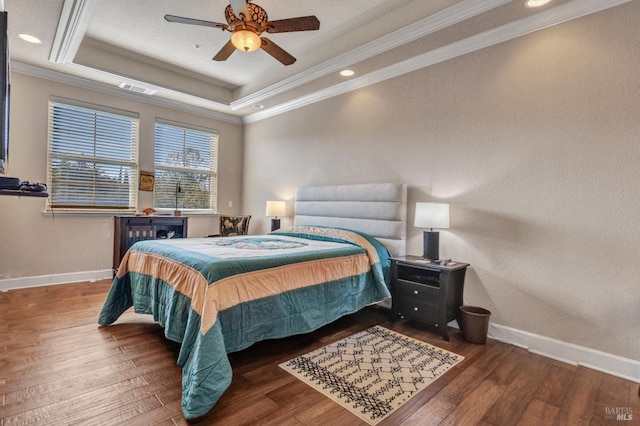 bedroom featuring hardwood / wood-style floors, a raised ceiling, crown molding, and baseboards