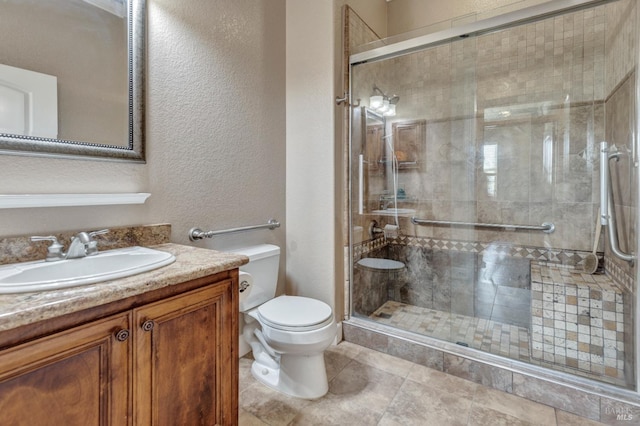 bathroom featuring toilet, a textured wall, a shower stall, and vanity
