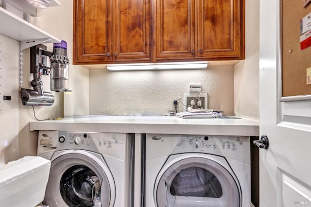 laundry room featuring a textured wall, separate washer and dryer, and cabinet space