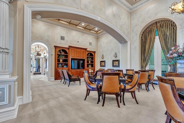 dining area featuring light colored carpet, coffered ceiling, arched walkways, an inviting chandelier, and a towering ceiling