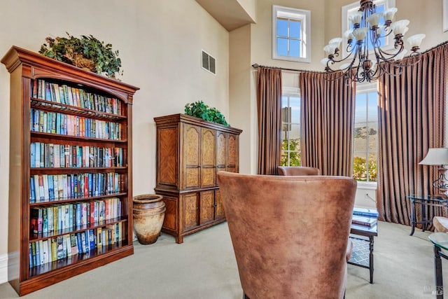 living area featuring an inviting chandelier, a wealth of natural light, light colored carpet, and visible vents