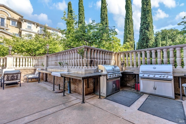 view of patio / terrace featuring a sink, fence, and exterior kitchen