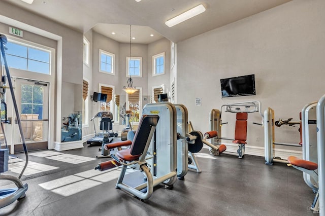 workout area with baseboards, recessed lighting, a high ceiling, and plenty of natural light