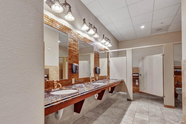 bathroom featuring visible vents, a drop ceiling, tile patterned flooring, and a sink