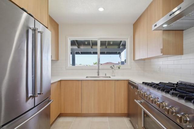 kitchen featuring a sink, under cabinet range hood, high end appliances, tasteful backsplash, and light countertops
