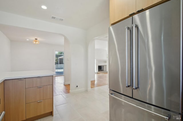 kitchen with recessed lighting, arched walkways, light countertops, high end refrigerator, and visible vents