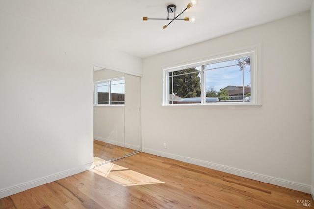 spare room featuring a chandelier, baseboards, wood finished floors, and a wealth of natural light