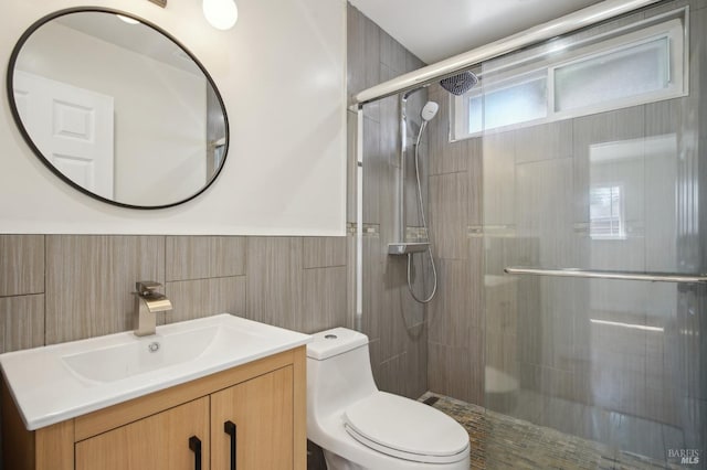 bathroom featuring a wainscoted wall, a stall shower, toilet, tile walls, and vanity