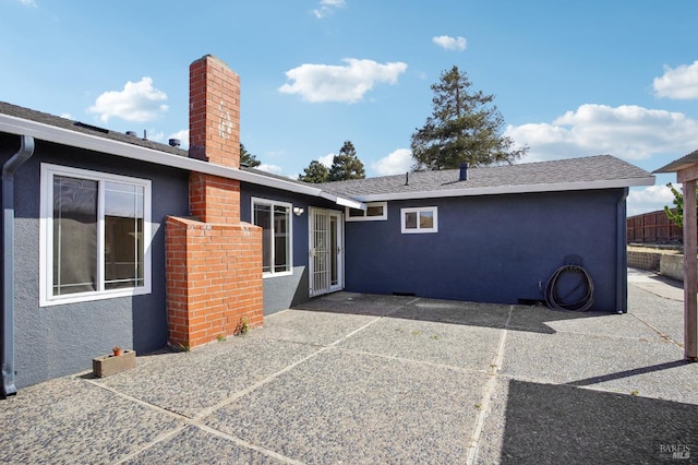rear view of house with a patio area, stucco siding, and a chimney