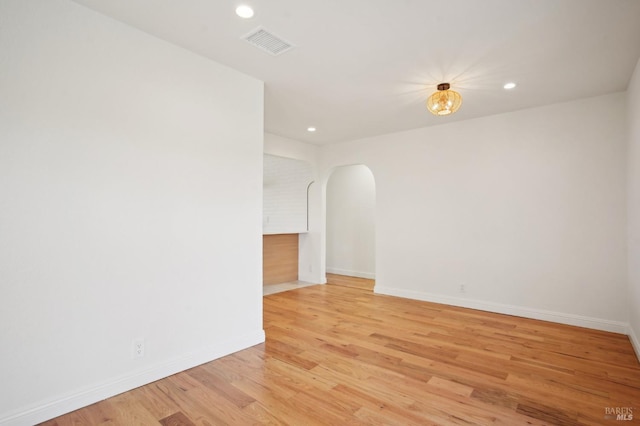spare room featuring recessed lighting, light wood-style floors, visible vents, baseboards, and arched walkways