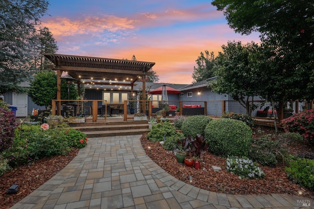 back of property at dusk featuring a pergola, a wooden deck, and fence