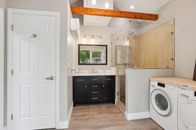 washroom with a wall mounted air conditioner, a sink, light wood-style floors, and washing machine and dryer