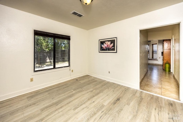 empty room featuring baseboards, visible vents, and light wood-type flooring