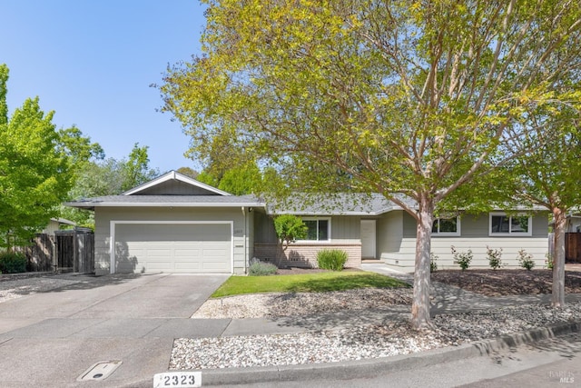 ranch-style home featuring brick siding, fence, driveway, and an attached garage