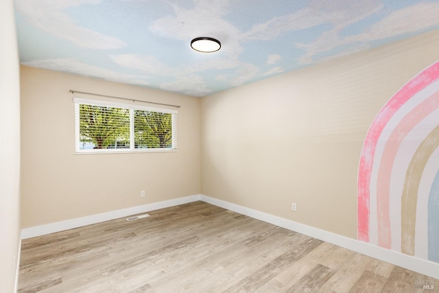 unfurnished room with baseboards, visible vents, and wood finished floors