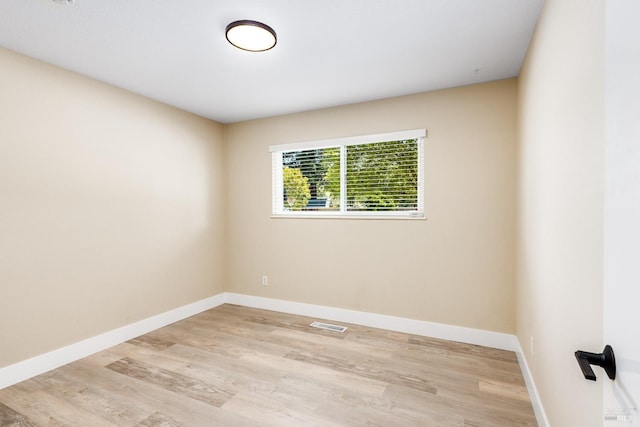 empty room featuring baseboards, visible vents, and light wood-style floors