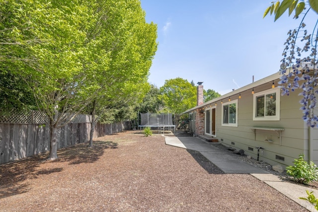 view of yard featuring fence, entry steps, a patio, and a trampoline