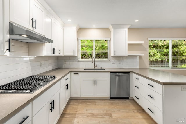 kitchen featuring stainless steel appliances, open shelves, under cabinet range hood, a sink, and a peninsula
