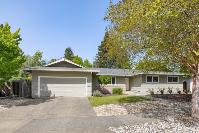 ranch-style home with concrete driveway, an attached garage, brick siding, and fence