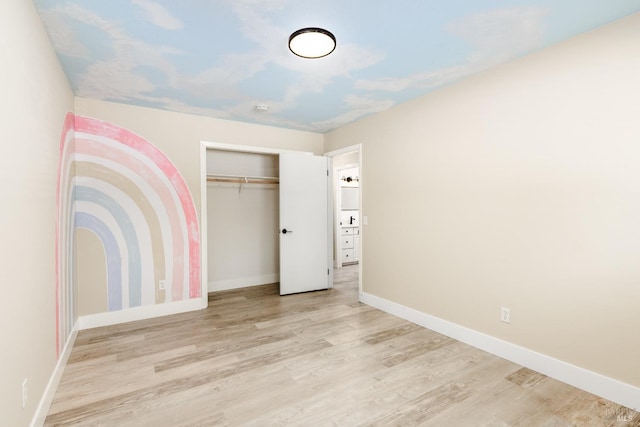 unfurnished bedroom with a closet, wood finished floors, and baseboards
