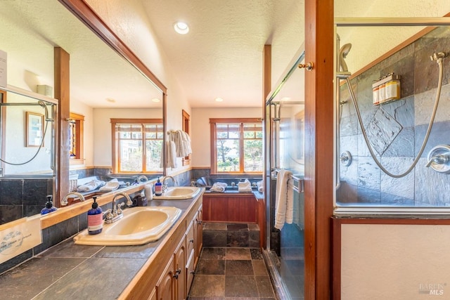 bathroom featuring double vanity, stone finish flooring, a shower stall, and a sink