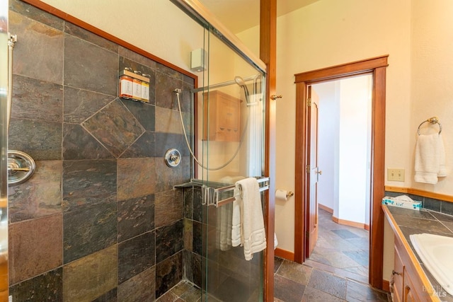 full bath with vanity, a shower stall, and stone tile flooring