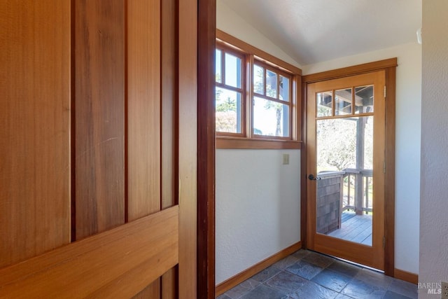 entryway featuring lofted ceiling, stone finish flooring, and baseboards
