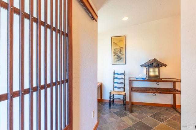 hall with stone finish flooring, recessed lighting, and baseboards