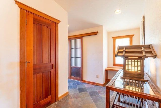 hall with recessed lighting, baseboards, and stone finish flooring