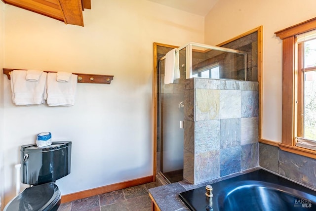 full bathroom featuring a bath, a shower stall, stone finish floor, and baseboards