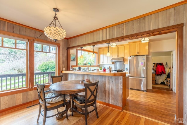 dining room featuring crown molding, wood walls, and light wood-type flooring