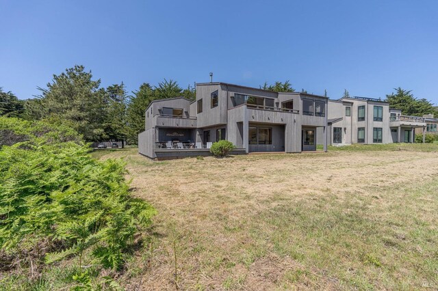 back of house with a lawn and a balcony