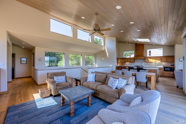 living room with recessed lighting, light wood-style floors, a ceiling fan, wood ceiling, and a towering ceiling