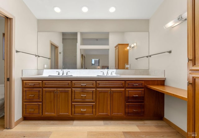 full bath featuring wood finished floors, toilet, double vanity, and a sink