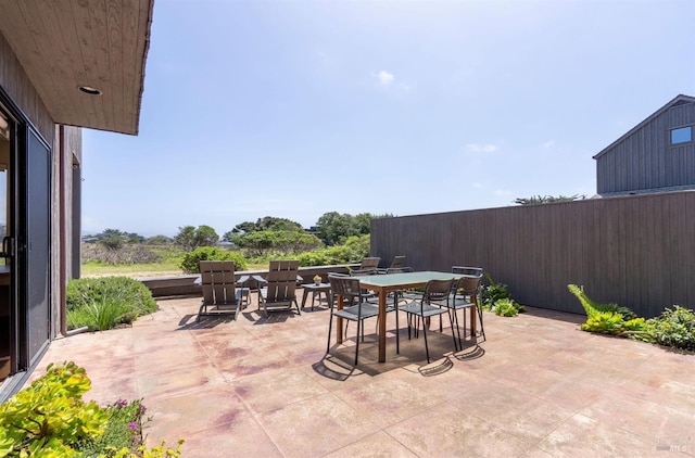 view of patio featuring outdoor dining space and fence